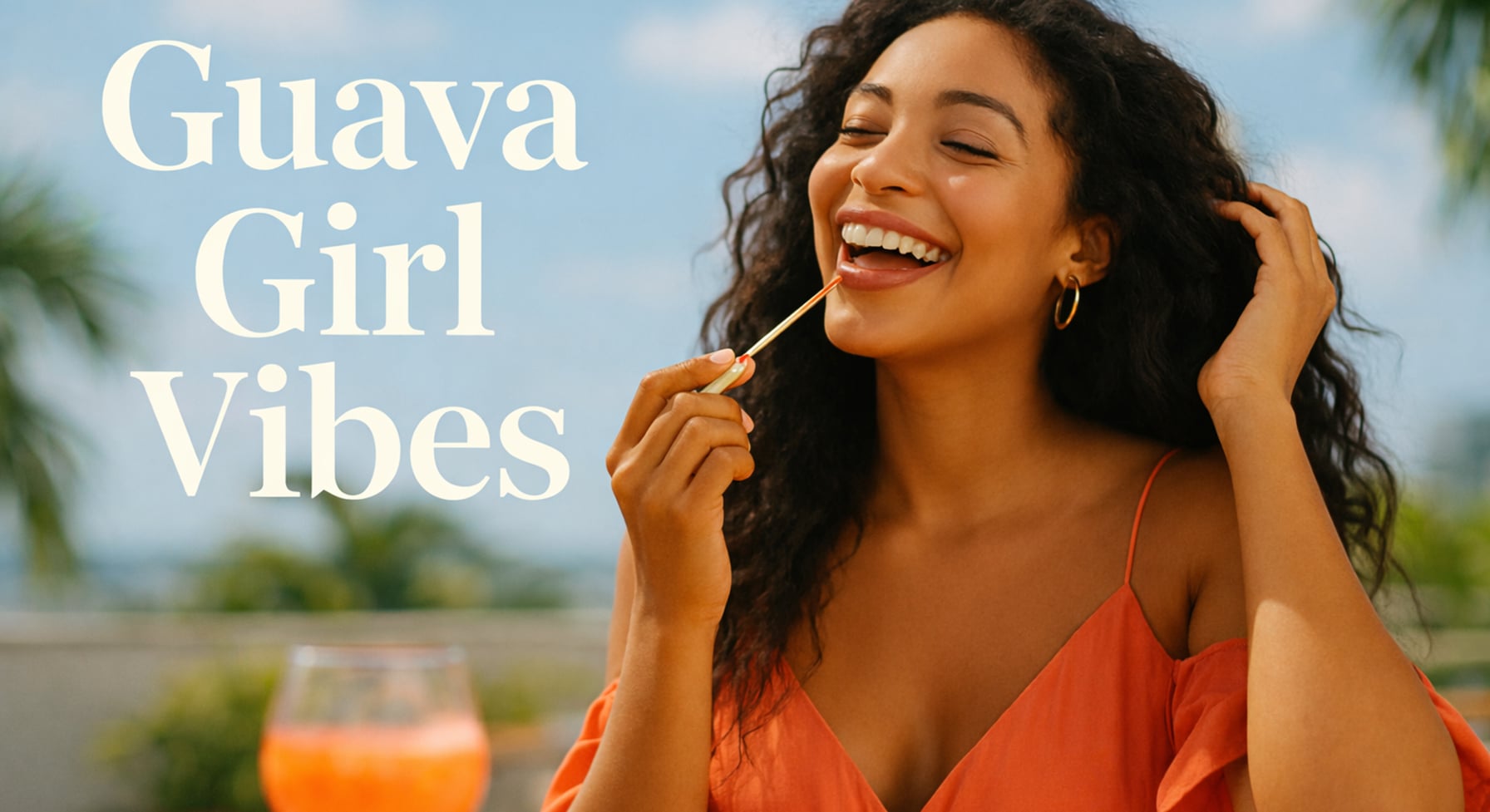 Smiling woman applying guava-pink lip gloss outdoors in warm sunlight, wearing a coral dress with tropical palms in the background.