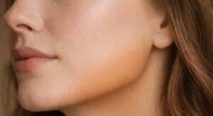 Close-up of foundation oxidizing on skin showing warm orange tone developing at the jawline against cooler skin tone at the cheek